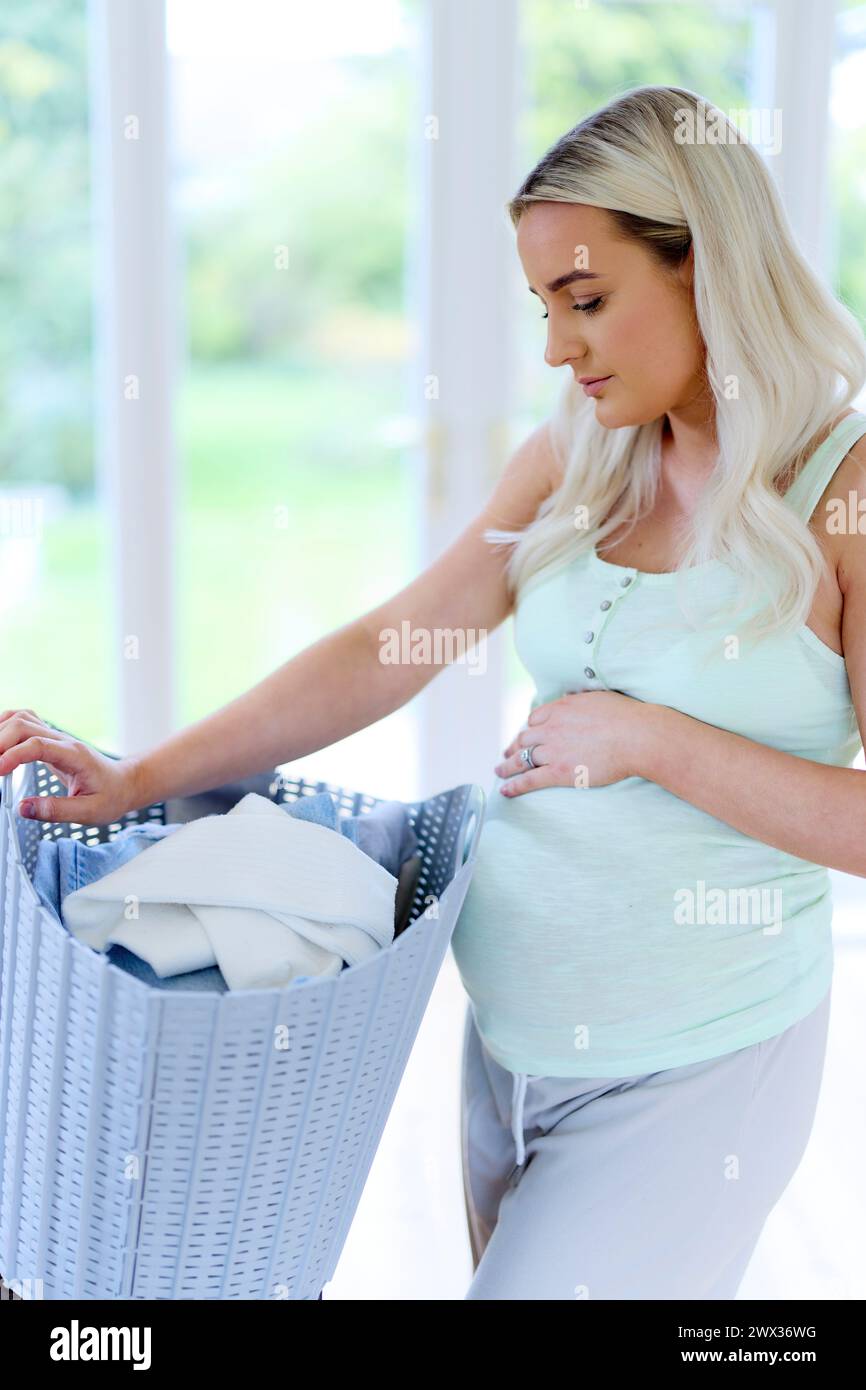 Müde schwangere Frau mit Waschkorb Stockfoto