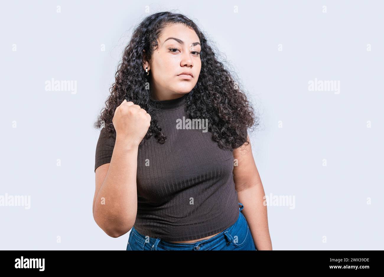 Wütende Frau, die mit der Faust bedroht, isoliert. Ein unzufriedenes Mädchen, das mit der Faust bedroht. Aggressives Personenkonzept Stockfoto