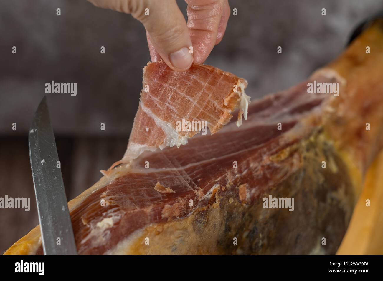 Mit spanischen Eicheln gefütterten iberischen Schinkenschinken Nahaufnahme offenes Messer, geschnitten von den Händen einer Wurstwarenfrau Stockfoto