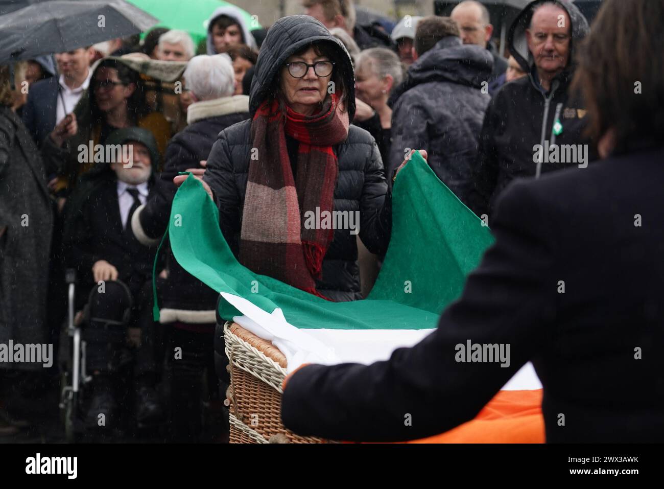 Die Trikolore werden aus dem Sarg der republikanischen Veteranen Rose Dugdale bei ihrer Beerdigung in der Crematorium Chapel in Glasnevin, Dublin, entfernt. Der englische Aristokrat, der einen berüchtigten IRA-Kunstraub führte, starb im Alter von 82 Jahren. Bilddatum: Mittwoch, 27. März 2024. Stockfoto