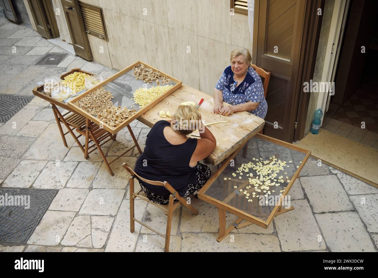 Zwei Frauen machen traditionelle frische Pasta namens „Orecchiette“ in einer Straße in der Altstadt von Bari Stockfoto