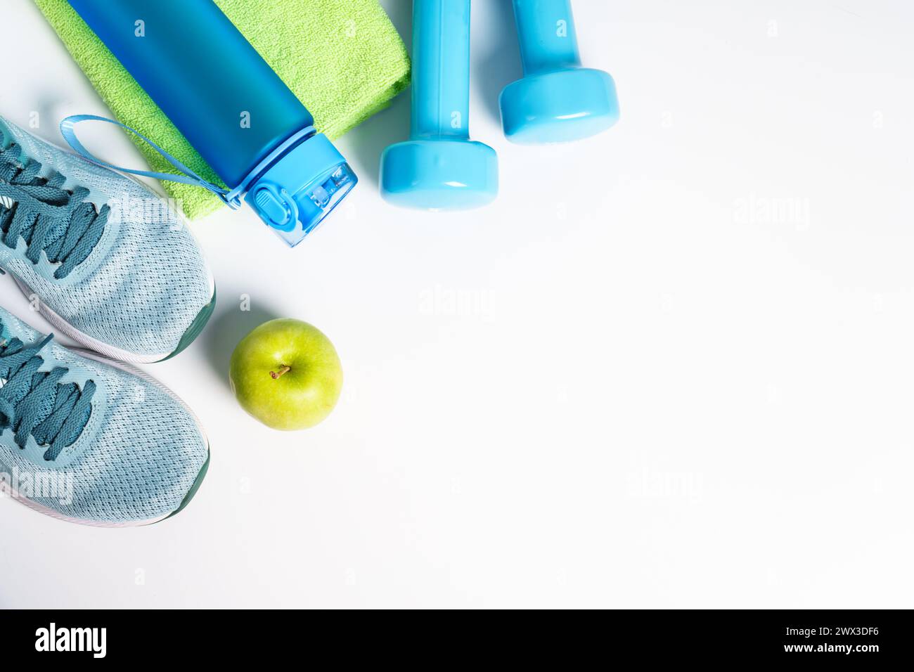 Turnschuhe, Kurzhanteln, grüner Apfel und Flasche Wasser isoliert auf weißem Hintergrund. Stockfoto