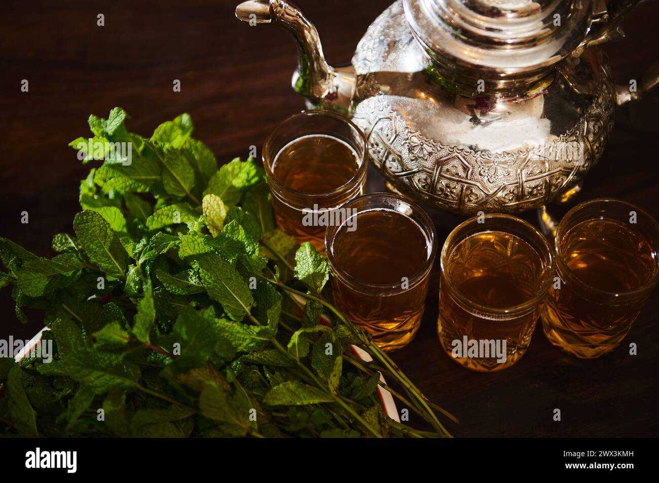 Blick von oben Trinkgläser mit frischem marokkanischem Tee mit Pfefferminz und Silber traditionelle Teekanne auf Holztisch. Genießen Sie eine Teepause im marokkanischen Tradi Stockfoto