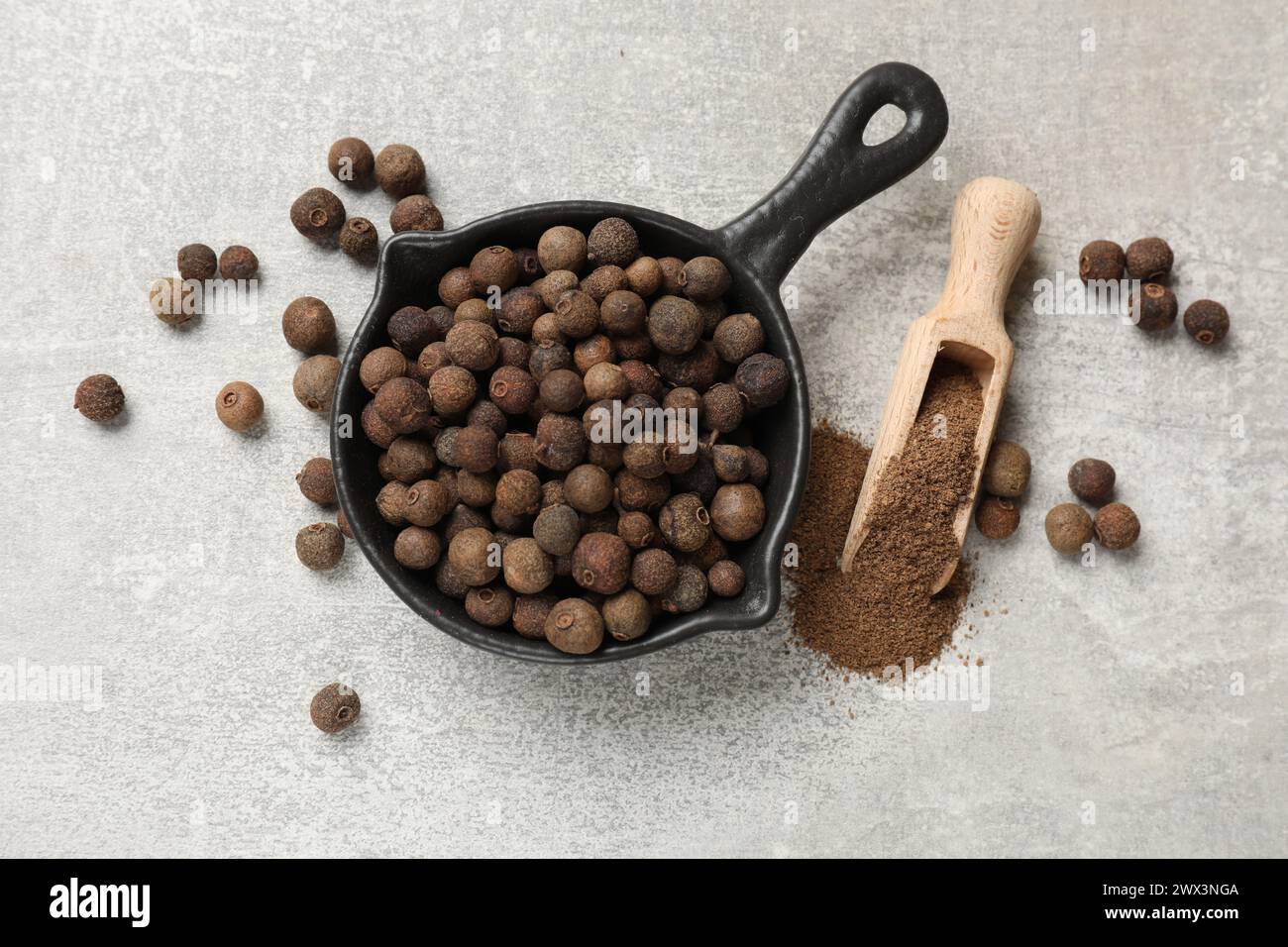 Gemahlener Allspice Pfeffer, Körner und Schaufel auf grauem Tisch, flach gelegt Stockfoto