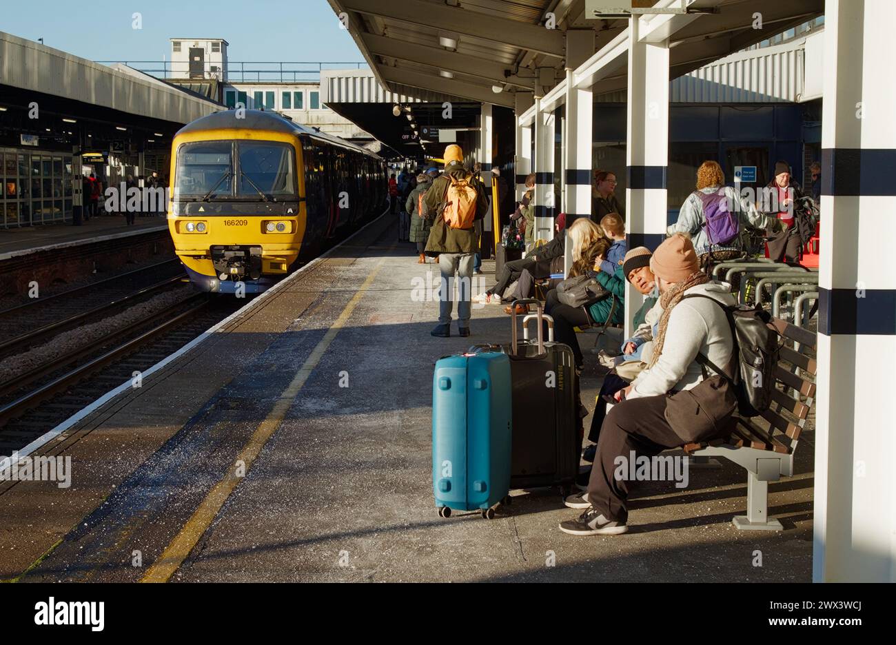 Passagiere mit Koffern, die als South Western Train (SWR) warten, kommen an Einem kalten Wintermorgen, UK, am Bahnhofssteig von Southampton an Stockfoto