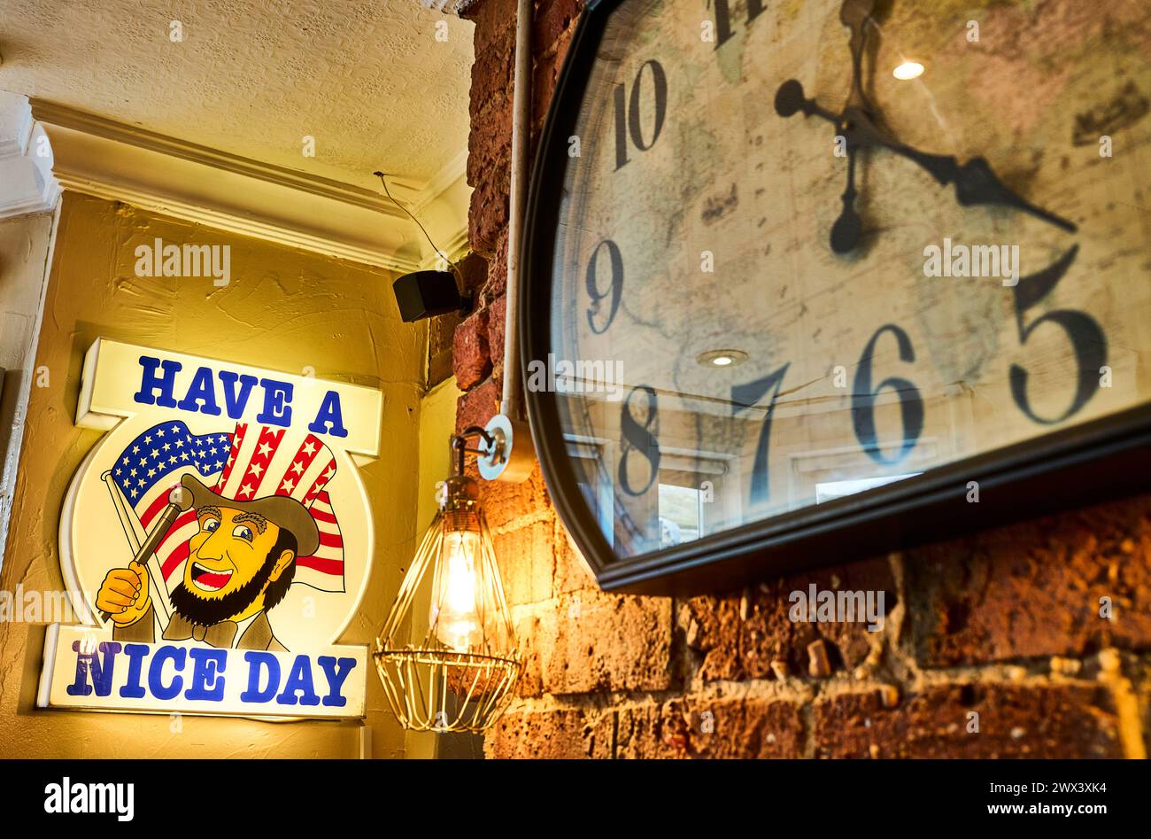 Ein schönes Tagesschild und eine alte Uhr an der Wand des britischen Pubs Stockfoto