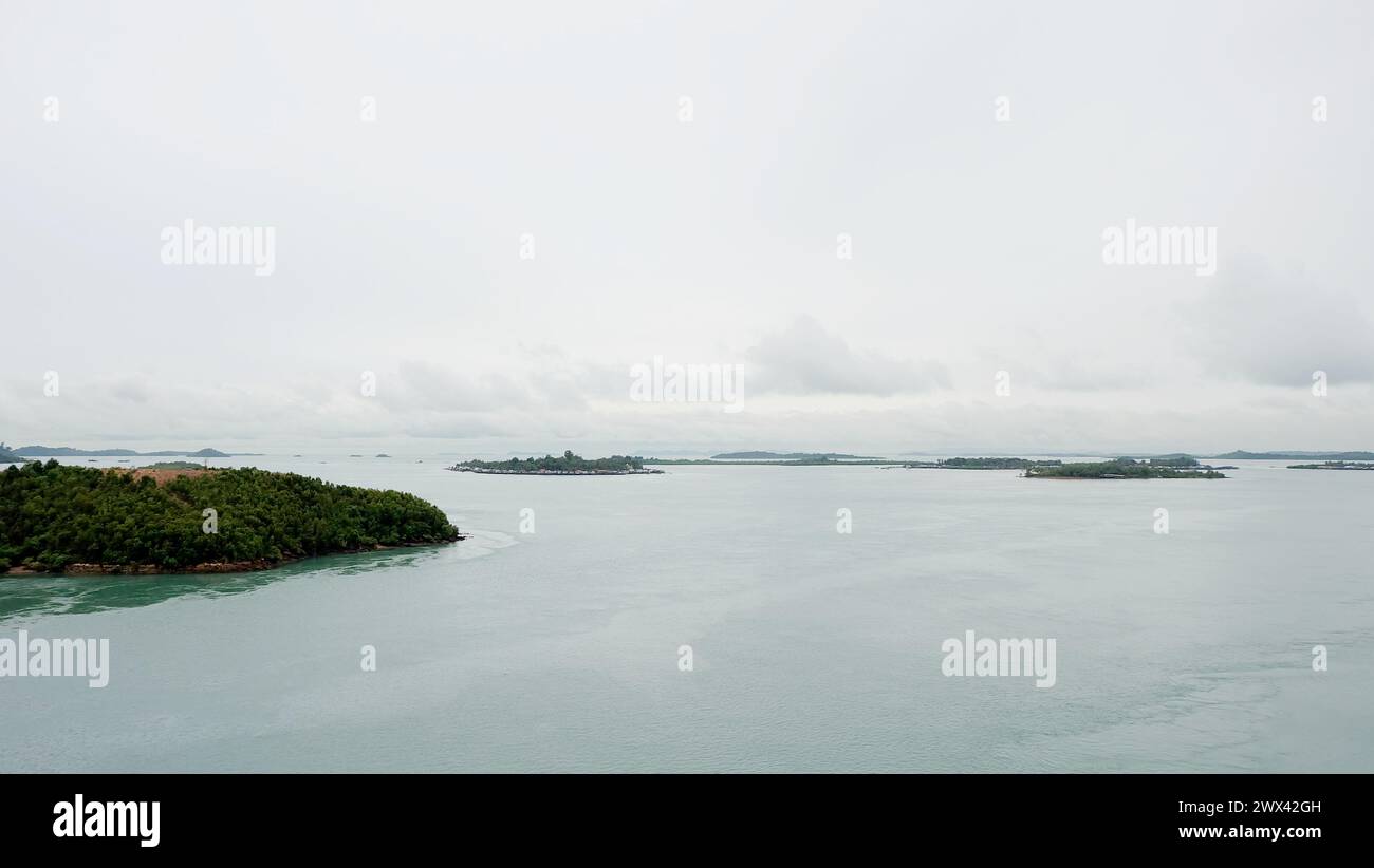 Gruppen von kleinen Inseln erstreckten sich bis zum Horizont, mit ruhigem Meer und düsterem Himmel. Blick von oben auf die Barelang Bridge, Indonesien. Stockfoto