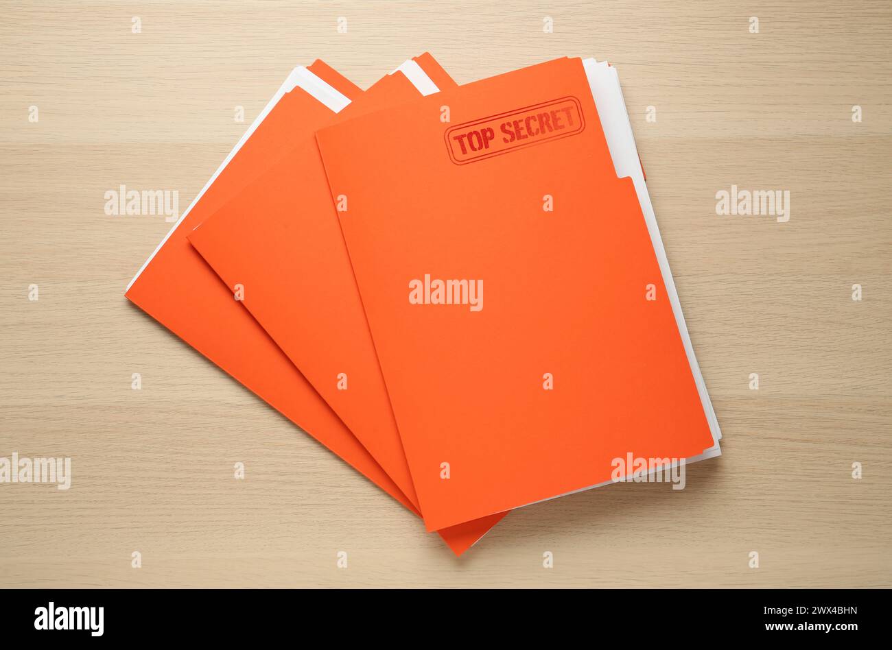 Streng geheimer Stempel. Orangefarbene Akten mit Dokumenten auf Holztisch, Draufsicht Stockfoto