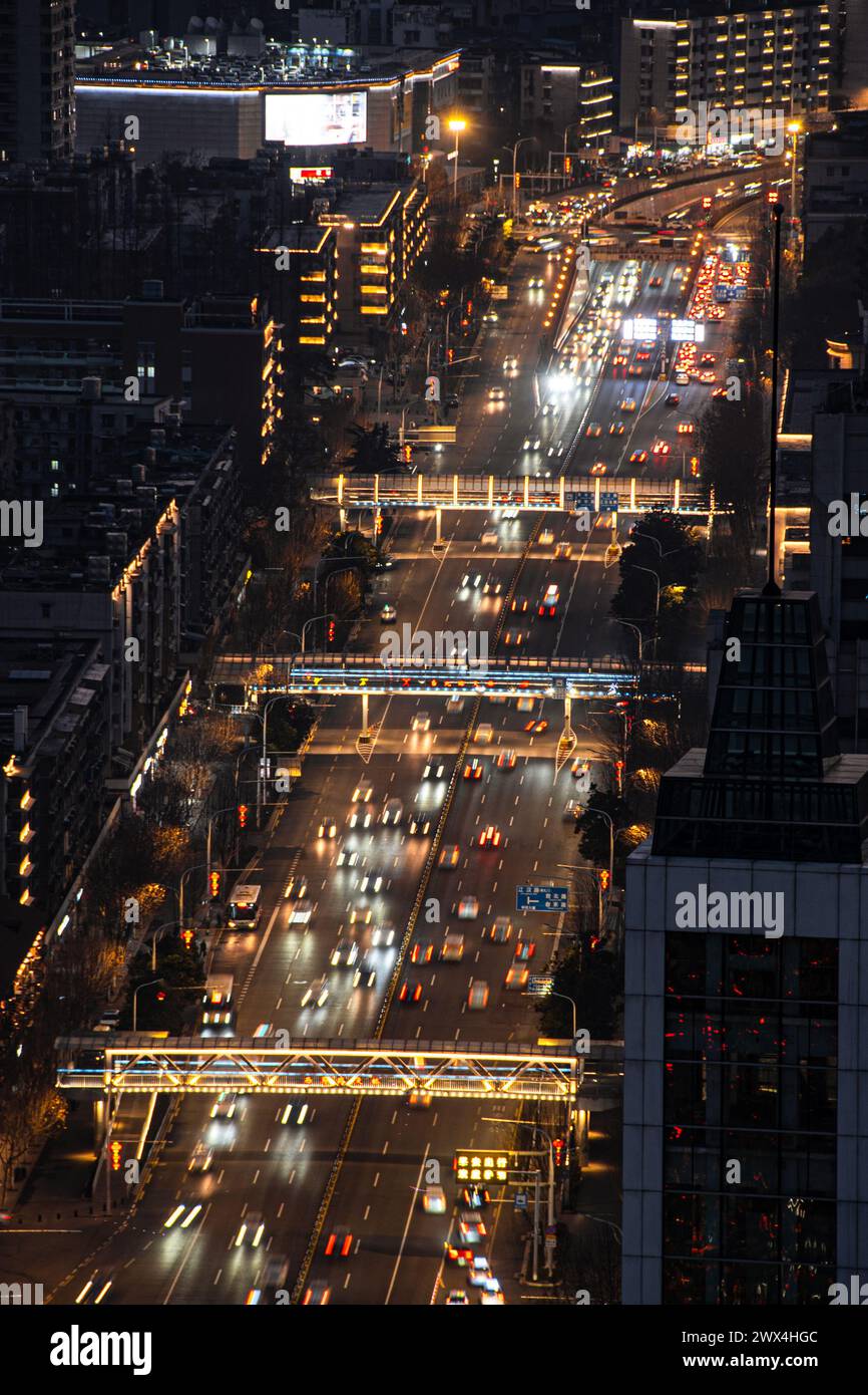 Die Kreuzung während der abendlichen Hauptverkehrszeit ist mit Fahrzeugen gefüllt. Über der Kreuzung befindet sich eine Fußgängerüberführung. Stockfoto