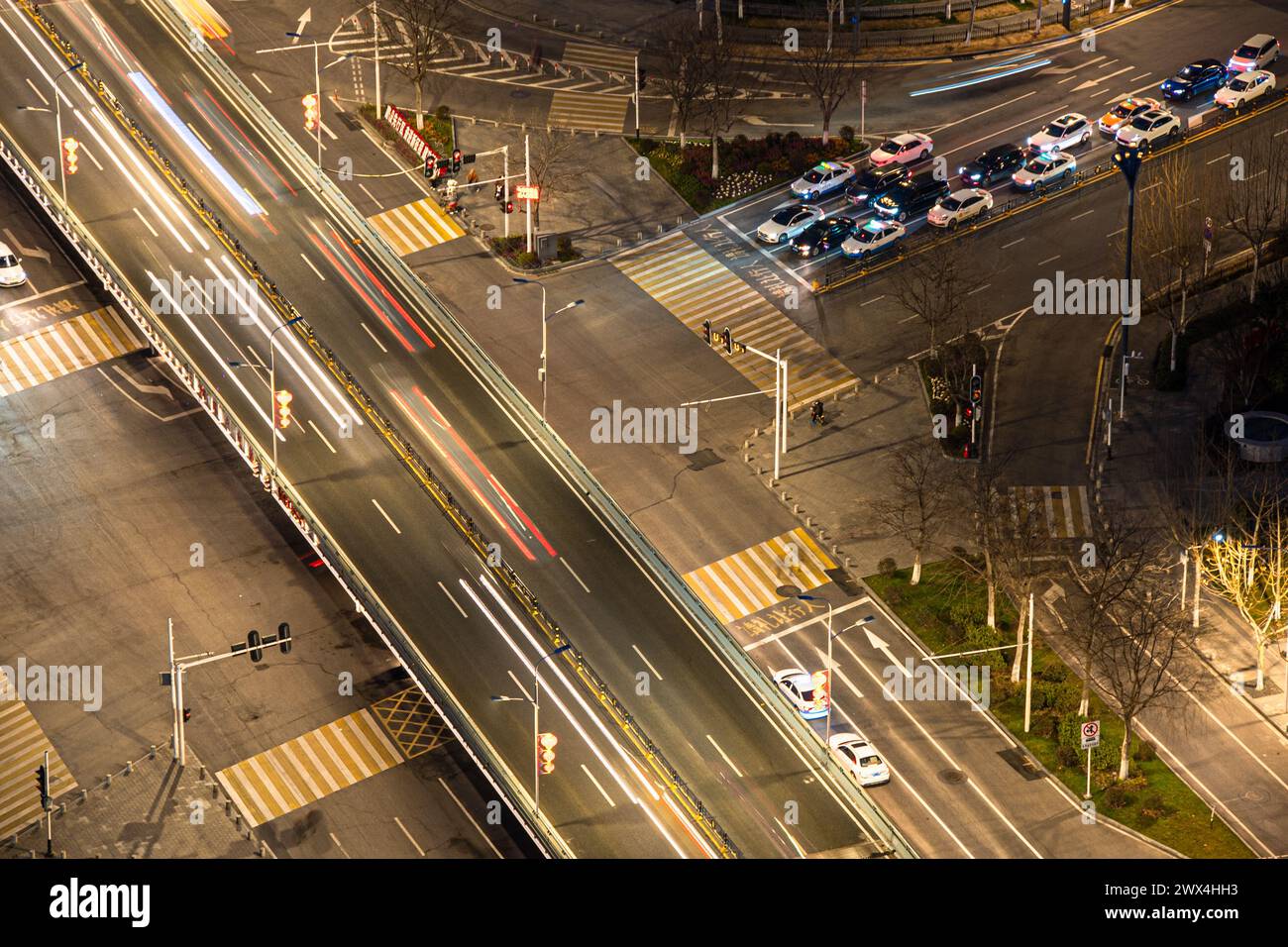 Die Kreuzung während der abendlichen Hauptverkehrszeit ist mit Fahrzeugen gefüllt. Über der Kreuzung befindet sich eine Fußgängerüberführung. Stockfoto