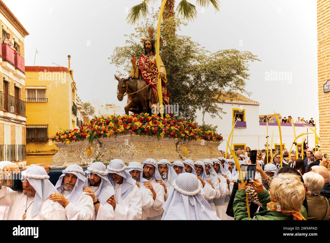 Almuneca, Spanien. Die Osterwoche in Almuneca, Spanien, beginnt mit dem ersten großen Ereignis, dem Palmensonntag (Domingo de Ramos), dem Feiertag, der genau eine Woche vor dem Ostersonntag stattfindet und an Jesu berühmten Einzug auf einem Esel in Jerusalem erinnert. Die Bruderschaften organisieren die Prozessionen, die jeden Tag durch die Straßen und Plätze ziehen, mit wunderschönen „Pasos“ und „Tronos“, die mit Blumen und religiösen Bildern geschmückt sind, die auf den Schultern der Teilnehmer getragen werden. Hier verlassen sie die Kirche des Encarnación in Almuñécar zu Beginn der Parade. März 2024 David Smith/Alamy Stockfoto