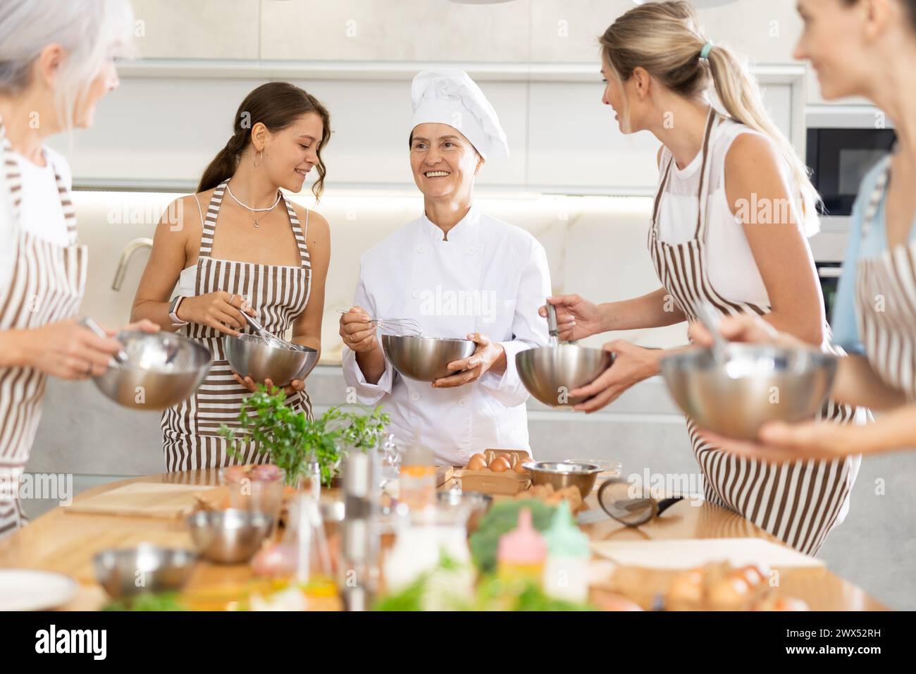 Reife weibliche Köchin mit Schüssel und Schneebesen Stockfoto