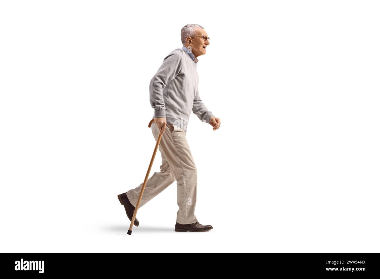 Profilaufnahme eines Reifen Gentlemans, der mit einem Stock auf weißem Hintergrund läuft Stockfoto