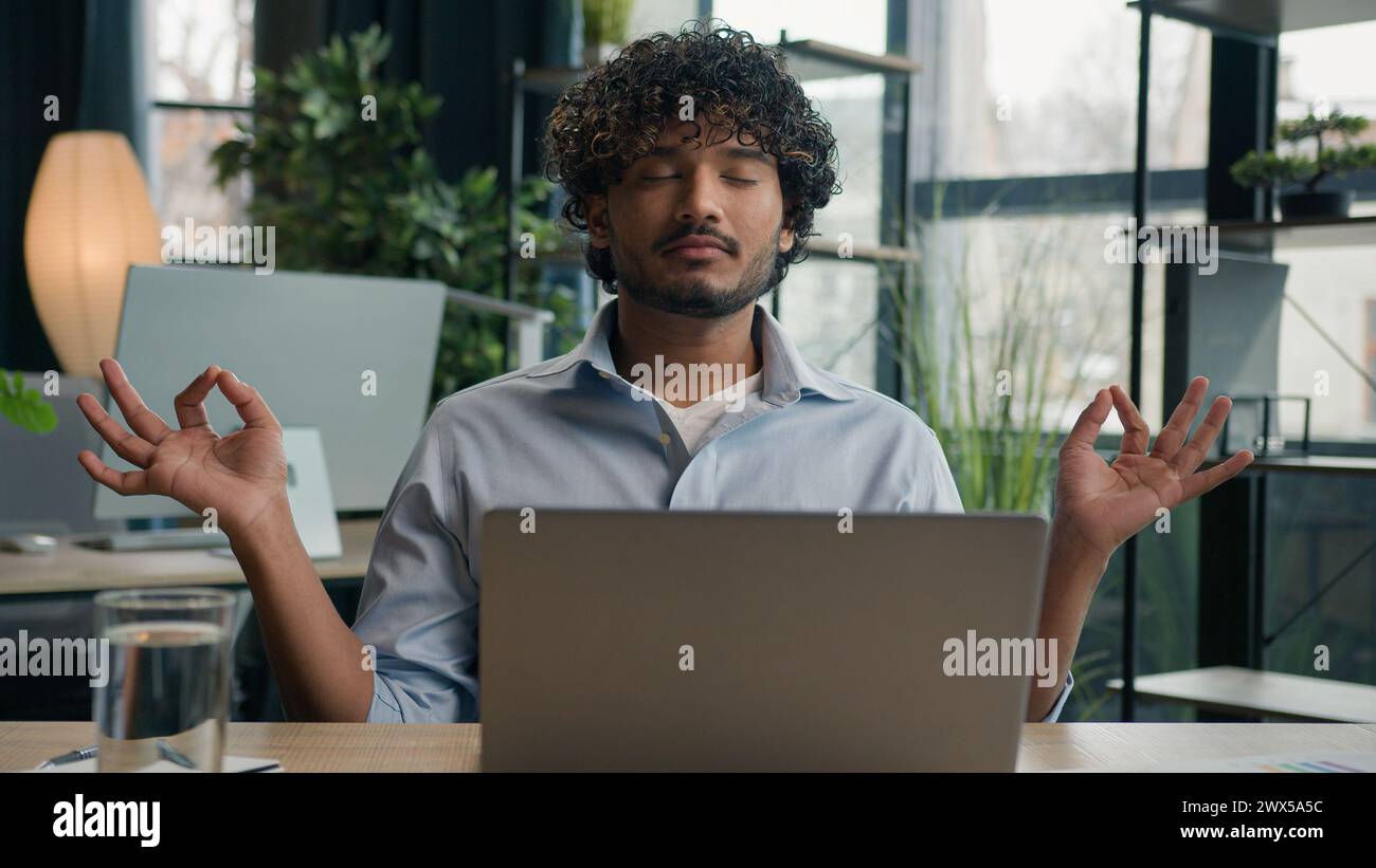 Ruhiger arabischer lateinischer Mann indischer Geschäftsmann Meditieren am Schreibtisch Zen Meditation entspannter männlicher Geschäftsmann CEO Arbeitgeber Kontrolle Emotionen reduzieren Stress Stockfoto