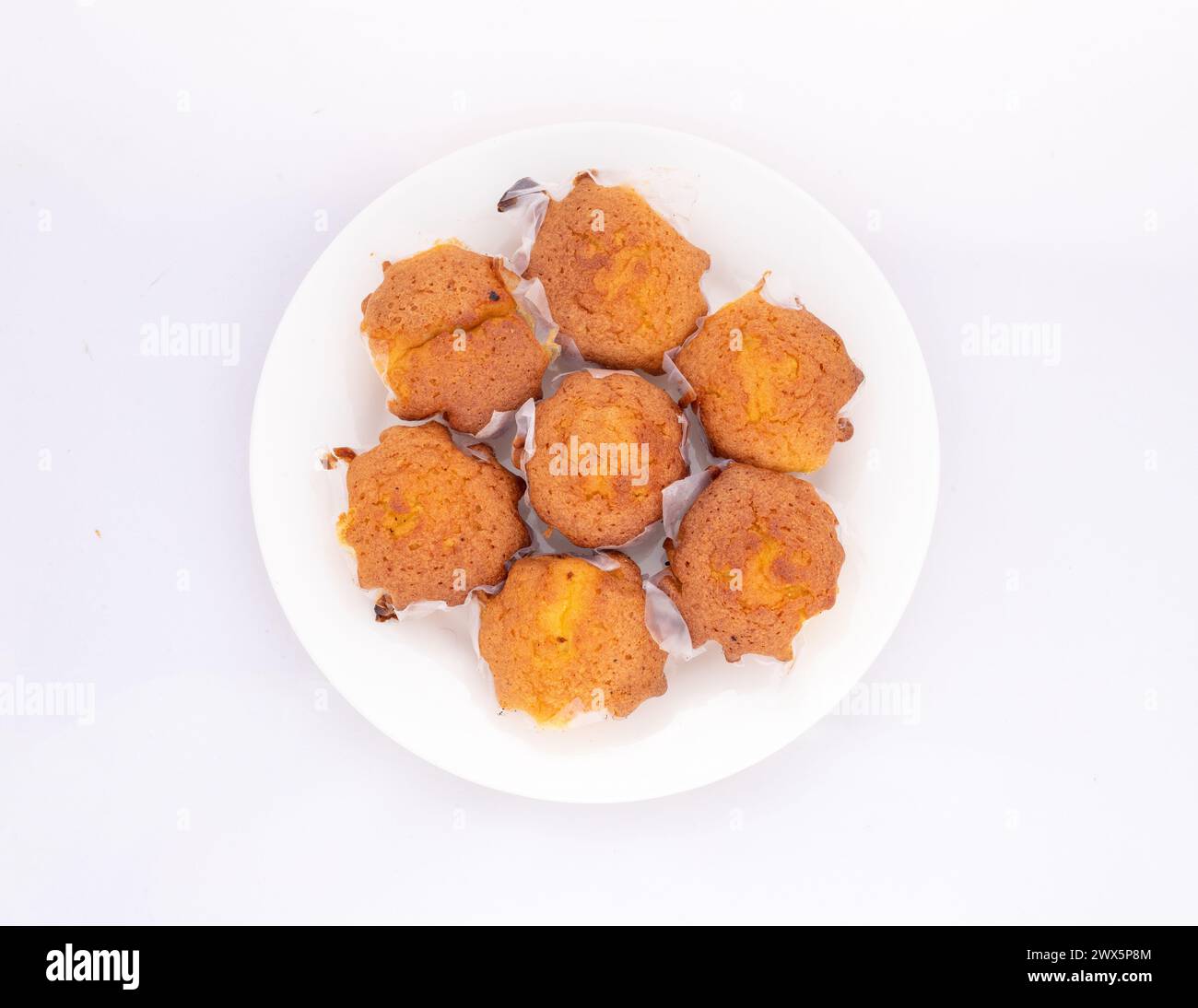 Hausgemachte Cupcakes in Keramikplatte auf weißem Hintergrund. Draufsicht. Stockfoto