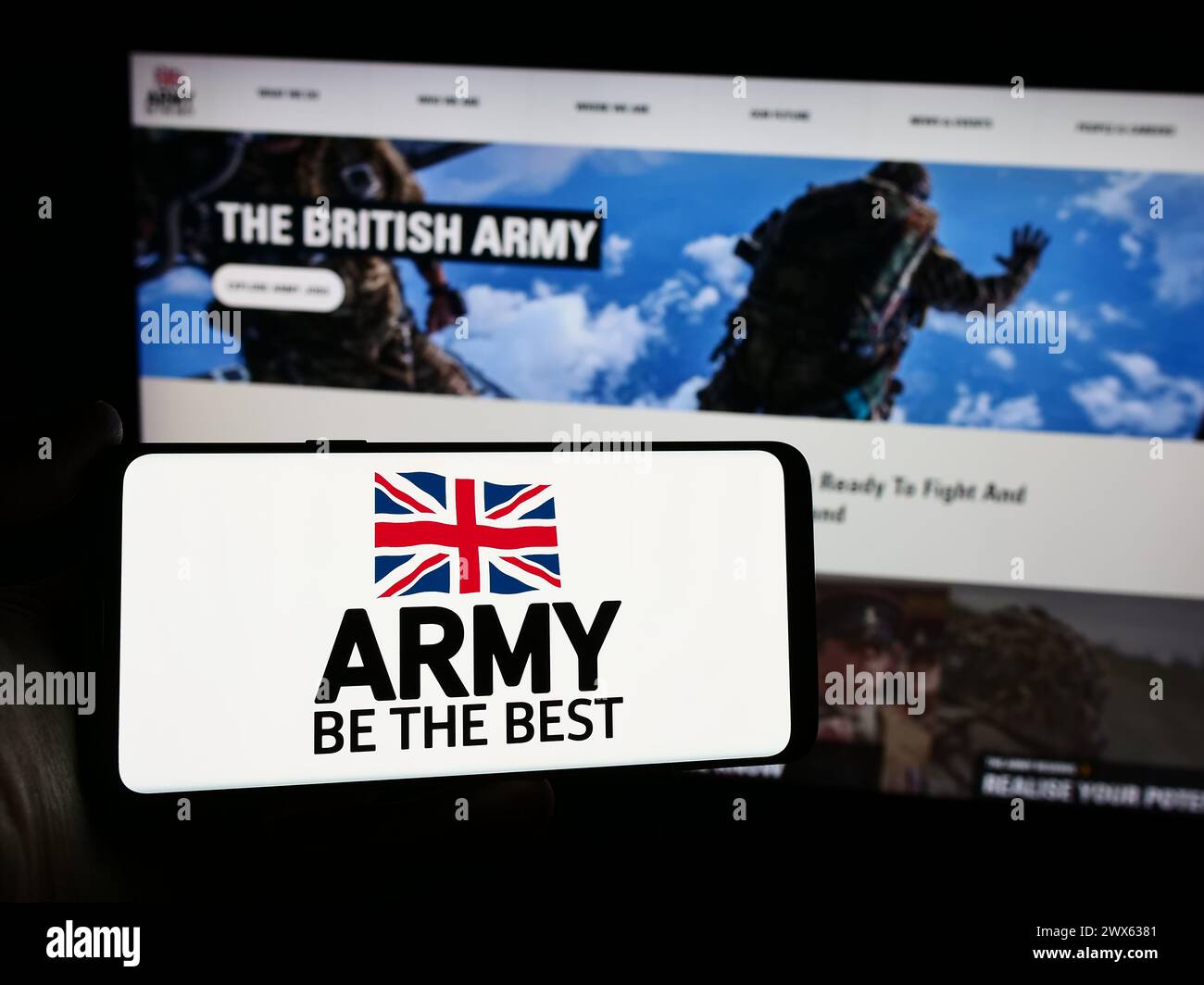 Person, die ein Smartphone mit dem Logo der britischen Bodentruppe vor der Website hält. Schwerpunkt auf dem Display des Telefons. Stockfoto