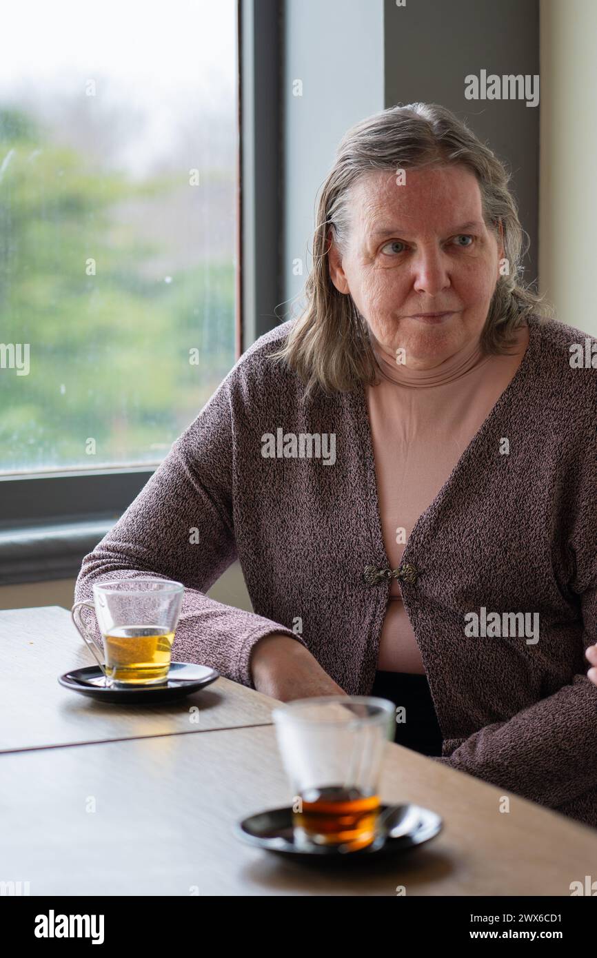 65-jährige Frau, die in einem Café sitzt und Tee trinkt Stockfoto