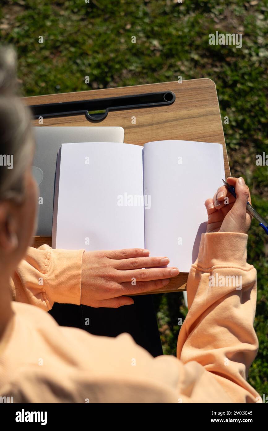 Frau mit einem leeren Notizbuch, die draußen arbeitet Stockfoto