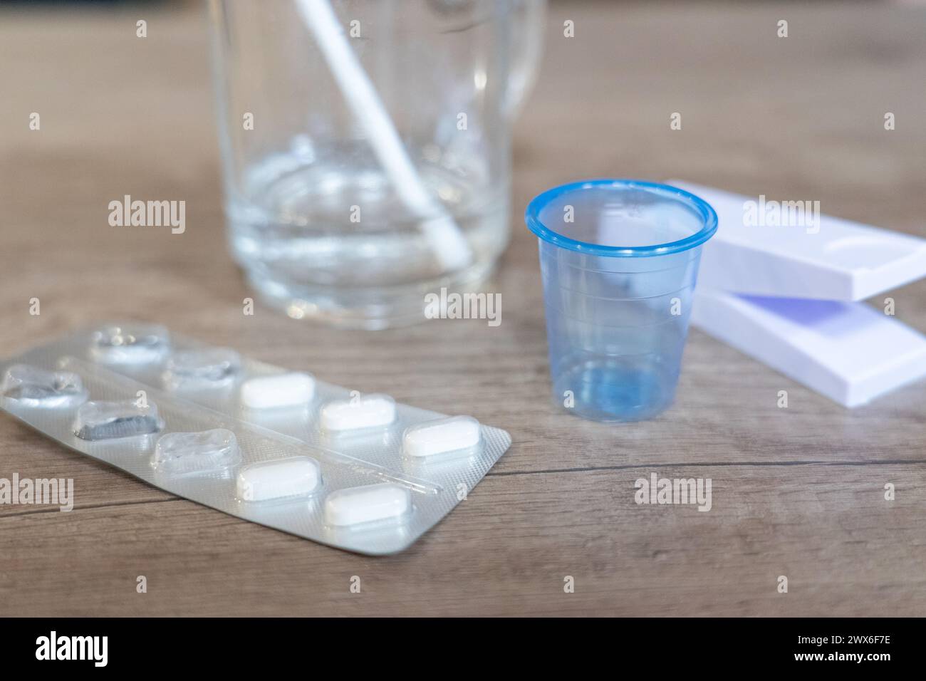 Pillen mit einem Glas Wasser, einem Pillenschneider und einem kleinen Glas Stockfoto