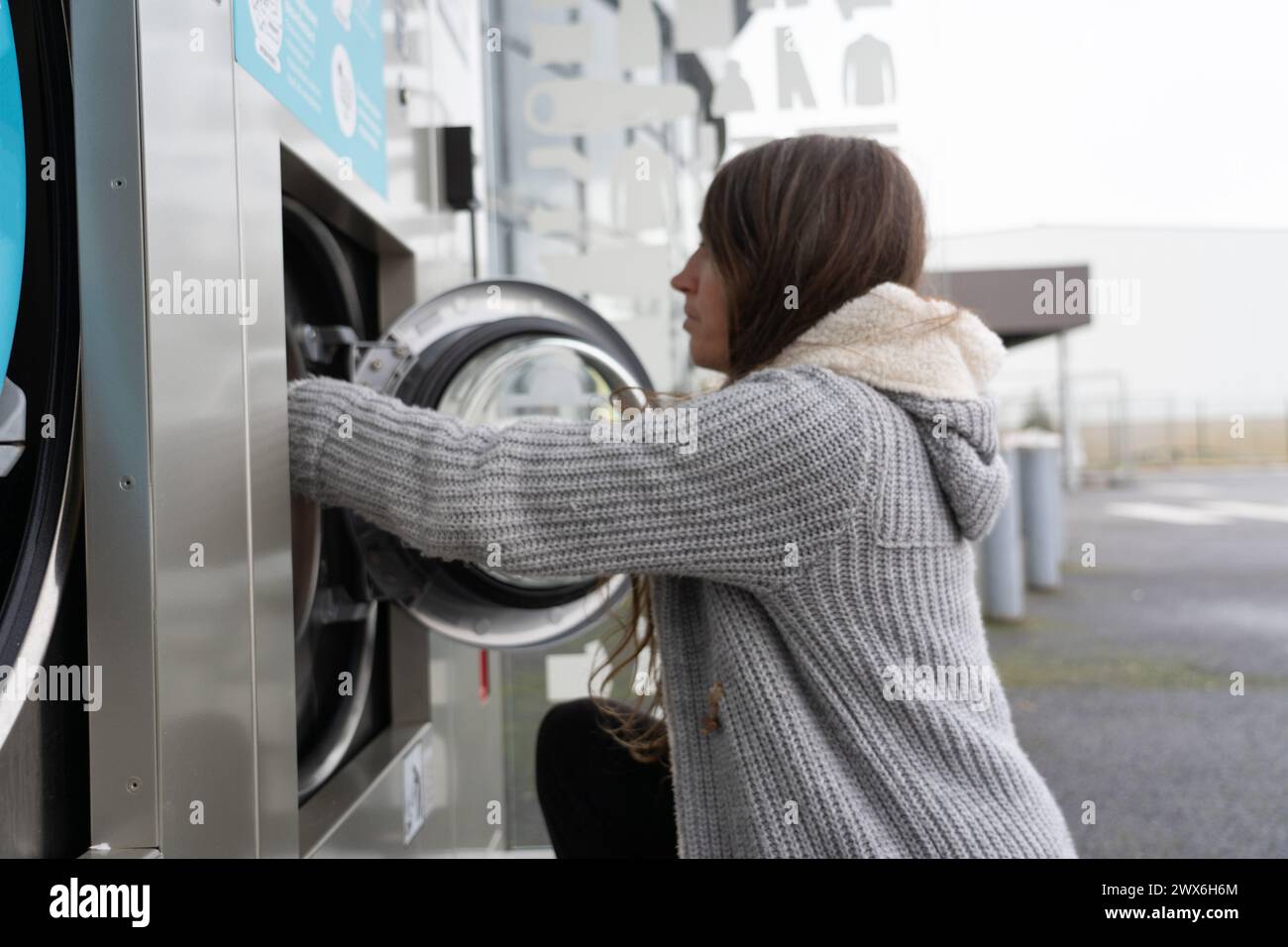 Frau, die Wäsche in einer Express-Wäsche macht Stockfoto