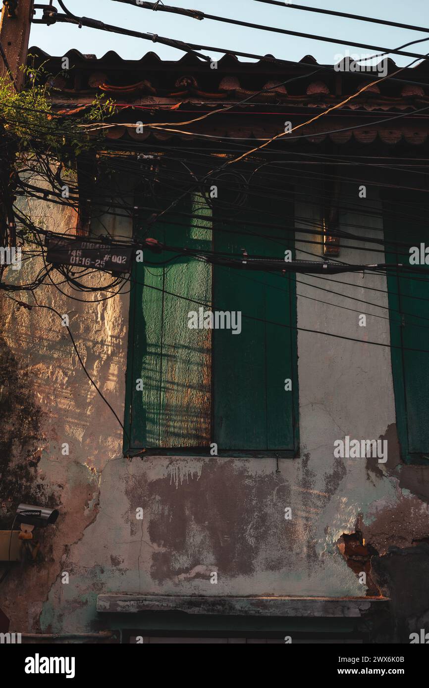 Ein Gebäude mit grünen Fenstern steht in der Nähe von Stromleitungen. Stockfoto