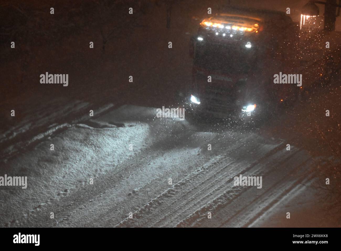 Lkw, der nachts in einem Schneesturm fährt, mit gelben Lichtern oben auf der Vorderseite der Fahrerkabine, um die Umrisse des Lkws aus Sicherheitsgründen anzuzeigen. Stockfoto
