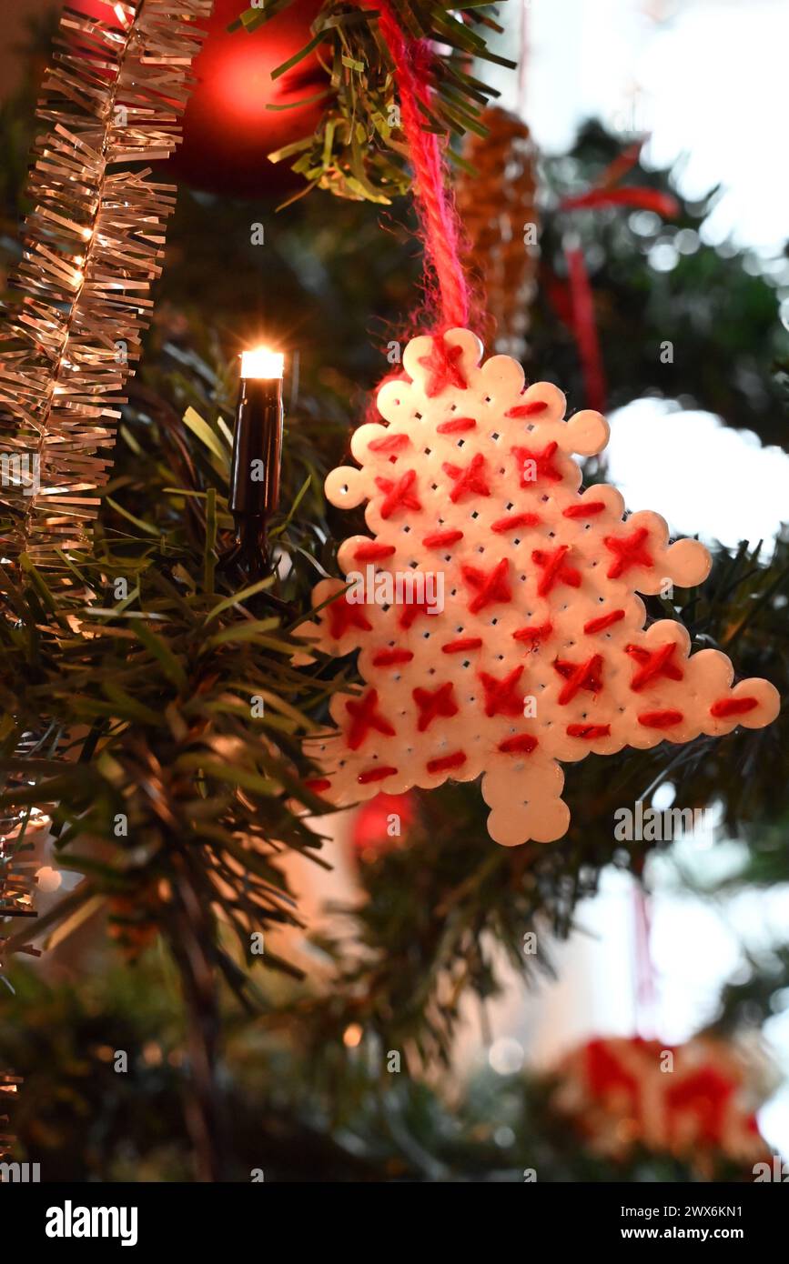 Handgefertigtes, perlenbesetztes Pixel-Art-Weihnachtsbaumschmuck mit Kreuzstickerei. Gemischte Techniken, Schmelzperlen mit rotem Baumwollgarn. Stockfoto