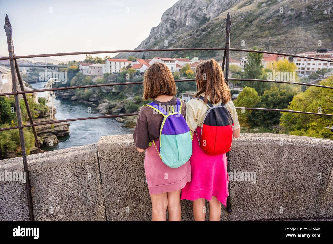 Zwillingsmädchen stehen auf der berühmten Mostar-Brücke und schauen auf die Stadt Mostar und den Fluss Neretva in Bosnien und Herzegowina. Die historische Mostar Bridge ist auch bekannt als Stockfoto