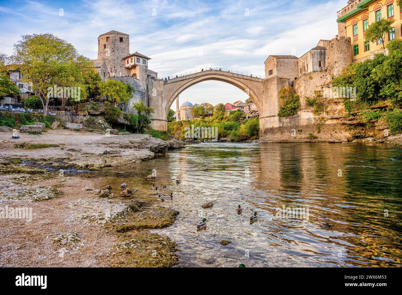 Historische Mostar Bridge, auch bekannt als Stari Most oder Old Bridge in Mostar, Bosnien und Herzegowina. Skyline von Mostar Häusern und Minaretten, bei Sonnenuntergang Stockfoto