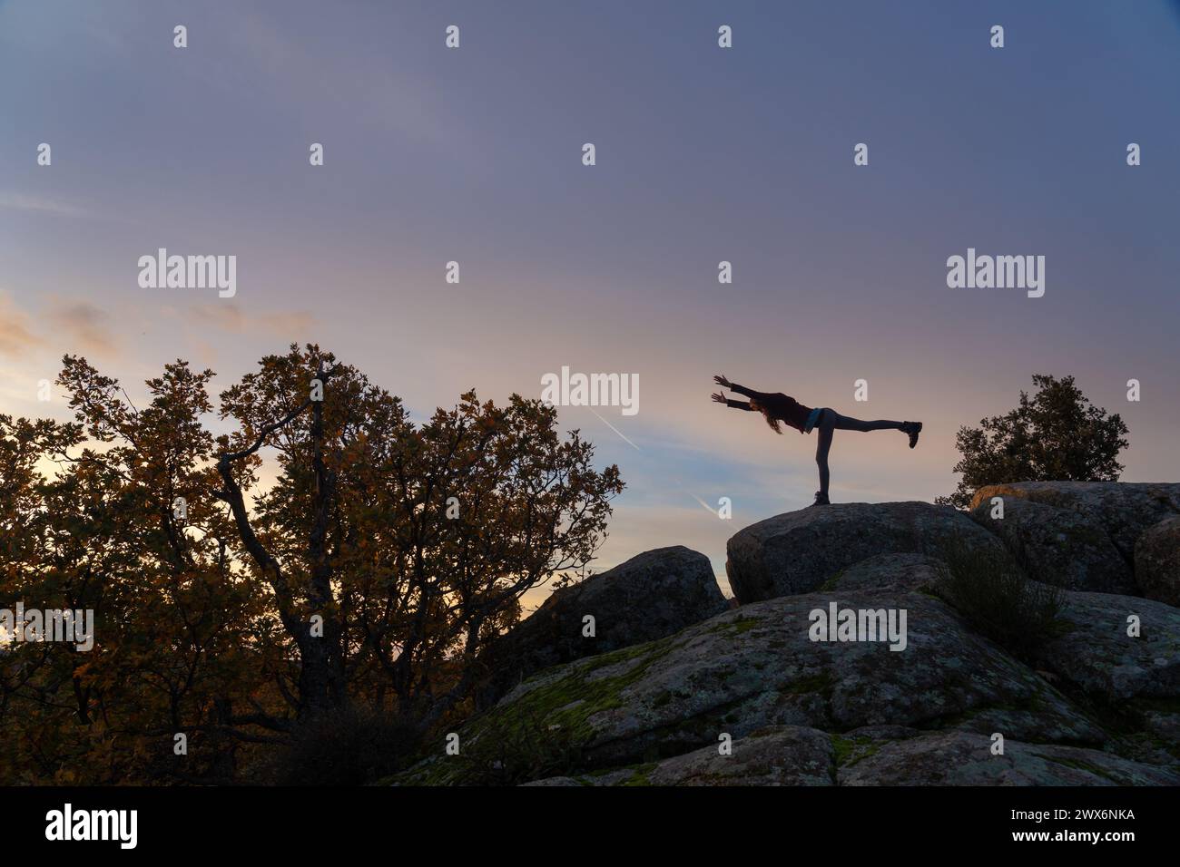 Silhouette einer Frau, die die Nummer drei Yogakriegerin bei Sonnenaufgang auf einem Berg in der Natur spielt Stockfoto