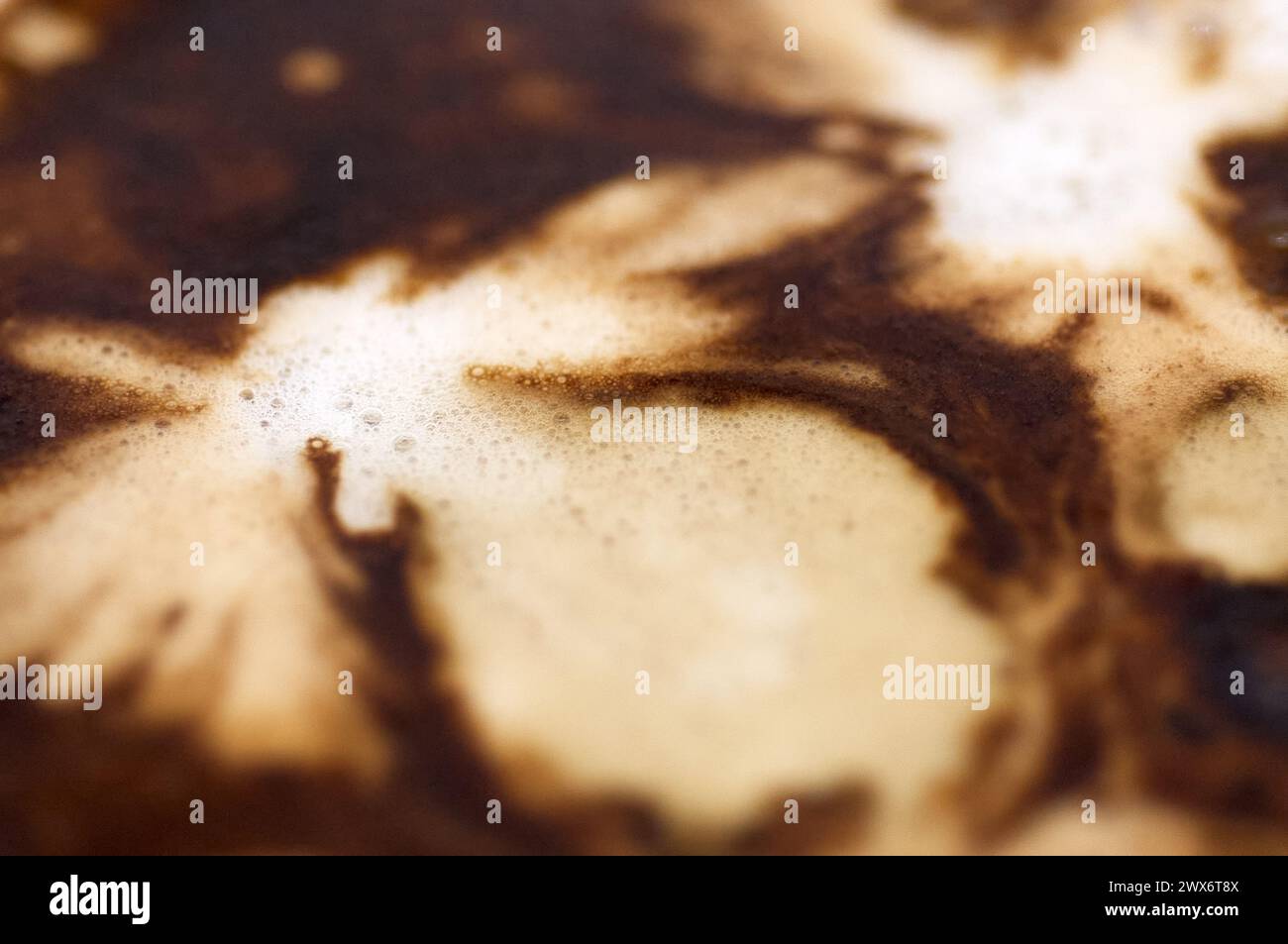 Das Bild zeigt einen Kaffee mit abstraktem Design im Schaumstoff, der einen faszinierenden visuellen Kontrast schafft, der zur Nachsicht einlädt. Stockfoto