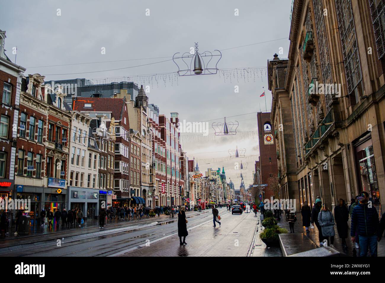 Der Amsterdamer Dome Square wird in Weihnachtslichtern lebendig, mit einer fröhlichen Straße voller Menschen, die die festliche Atmosphäre der Urlaubsmeere einfangen Stockfoto