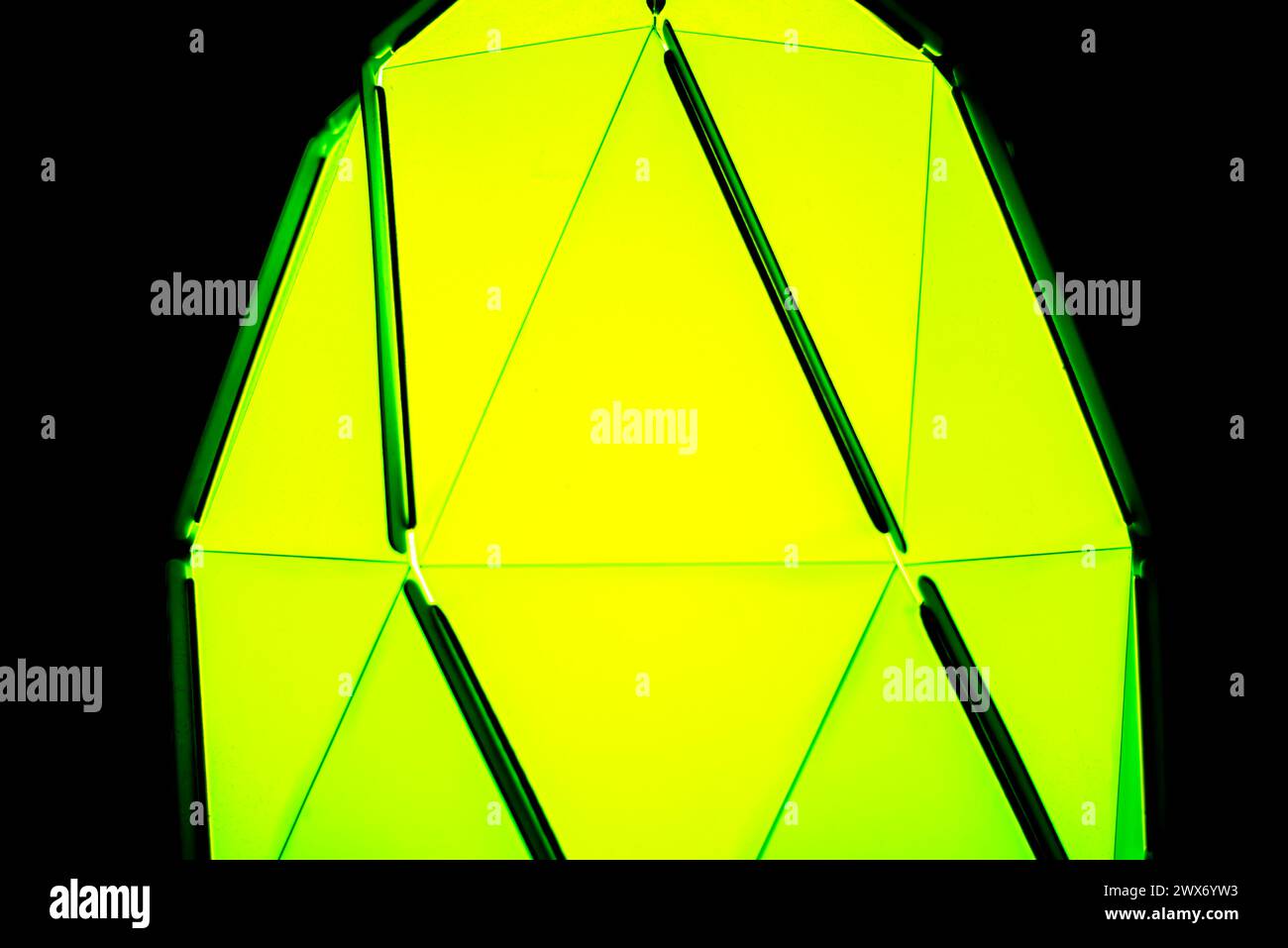 Ein leuchtendes grünes Licht durchdringt die geheimnisvolle Dunkelheit und erzeugt einen leuchtenden Kontrast zum tiefschwarzen Hintergrund. Stockfoto