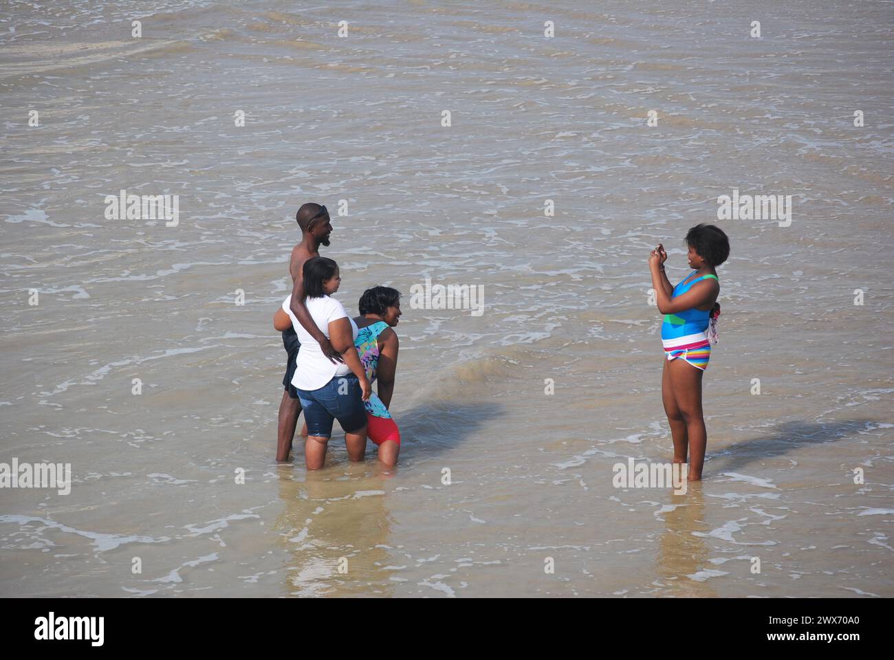 Junge Leute am Meer, die scherzen und Fotos machen Stockfoto