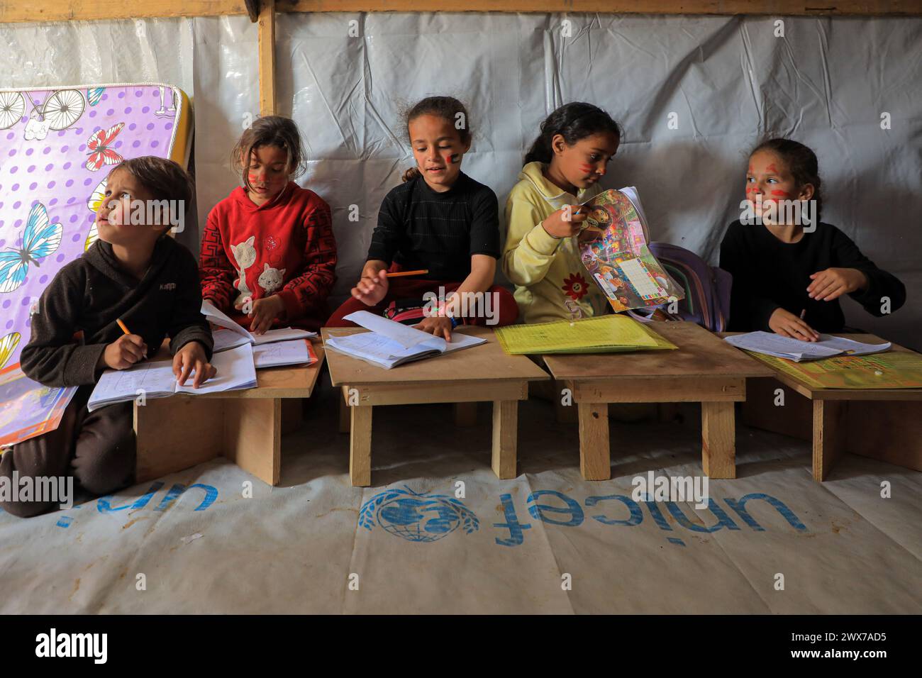 (240328) -- RAFAH, 28. März 2024 (Xinhua) -- palästinensische Kinder studieren in einem temporären Klassenzimmer im südlichen Gazastreifen, Stadt Rafah, 27. März 2024. Die schwere Bombardierung von Gaza durch Israel hat zu "direkten Schlägen" auf 212 Schulen innerhalb der Enklave geführt, so eine Analyse, die am Mittwoch in Zusammenarbeit mit den Vereinten Nationen veröffentlicht wurde. Satellitenbilder haben gezeigt, dass seit Beginn des Konflikts am 7. Oktober 2023 mindestens 53 Schulen „vollständig zerstört“ wurden. (Foto: Rizek Abdeljawad/Xinhua) Stockfoto