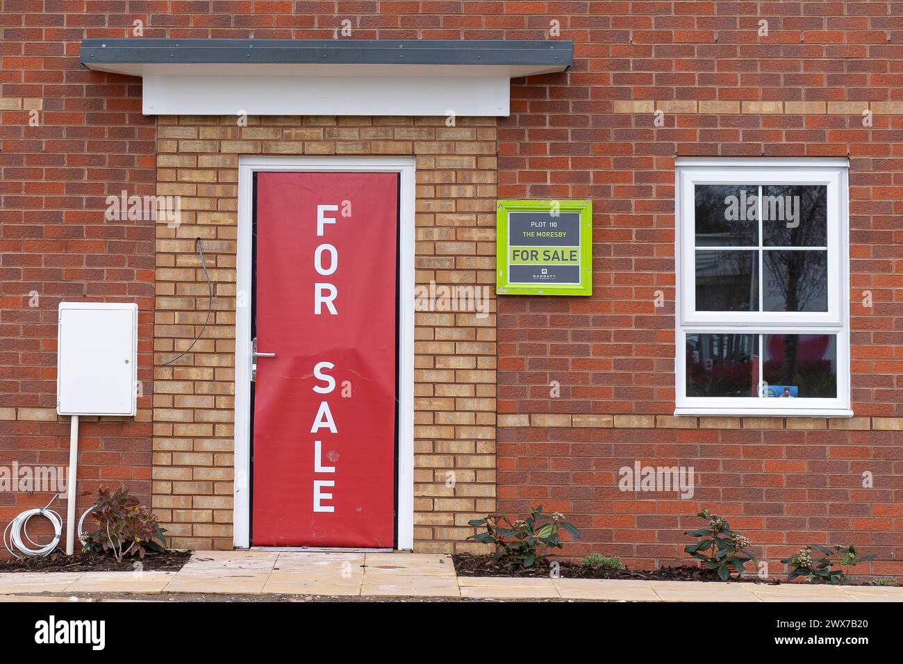 Nahaufnahme eines „for Sale“-Schilds, das die gesamte Eingangstür eines neu erbauten Wohnhauses/Hauses auf britischem Gebiet (Barratt Homes) abdeckt. Stockfoto