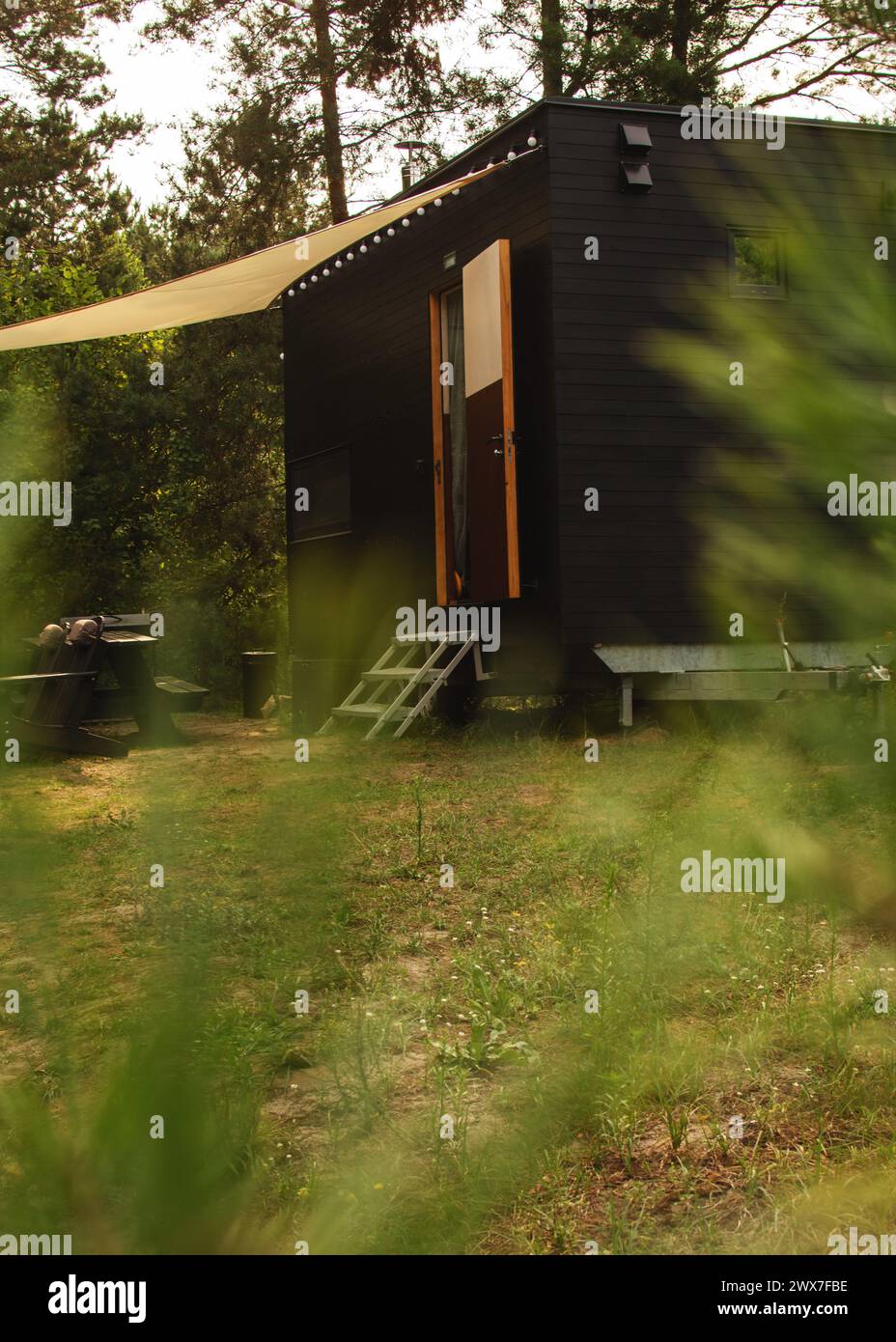 Eine modulare Rahmenwohnung auf Rädern, mit Holz vor dem Hintergrund eines Herbstwaldes gesäumt. Mobiler ökologischer Raum für Wohnen und Tourismus Stockfoto