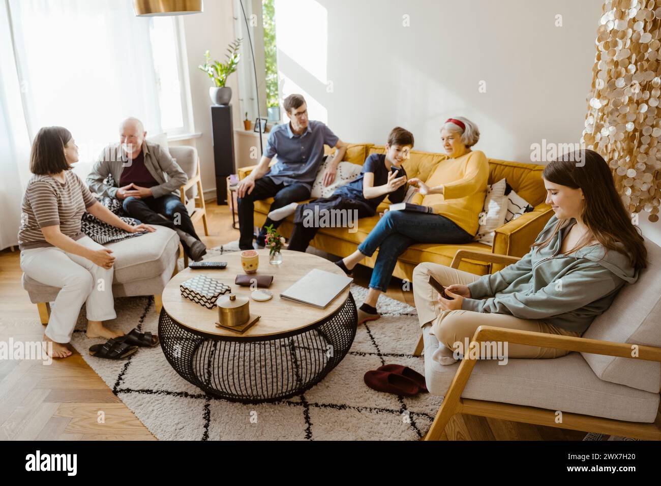 Familie mehrerer Generationen mit schnurlosen Technologien und Gesprächen im Wohnzimmer zu Hause Stockfoto