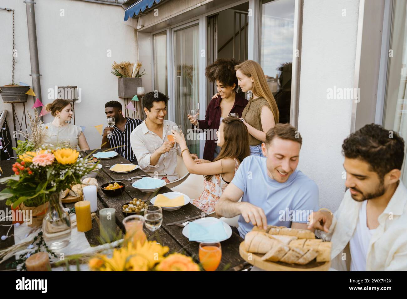Gruppe von männlichen und weiblichen multirassischen Freunden, die Essen und Trinken auf der Dinnerparty auf dem Balkon essen Stockfoto
