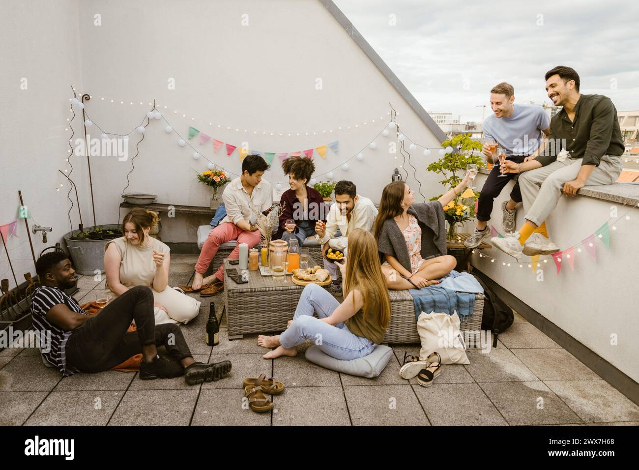 Gruppe von multirassischen Freunden, die Spaß beim Feiern während der Party auf dem dekorierten Balkon haben Stockfoto