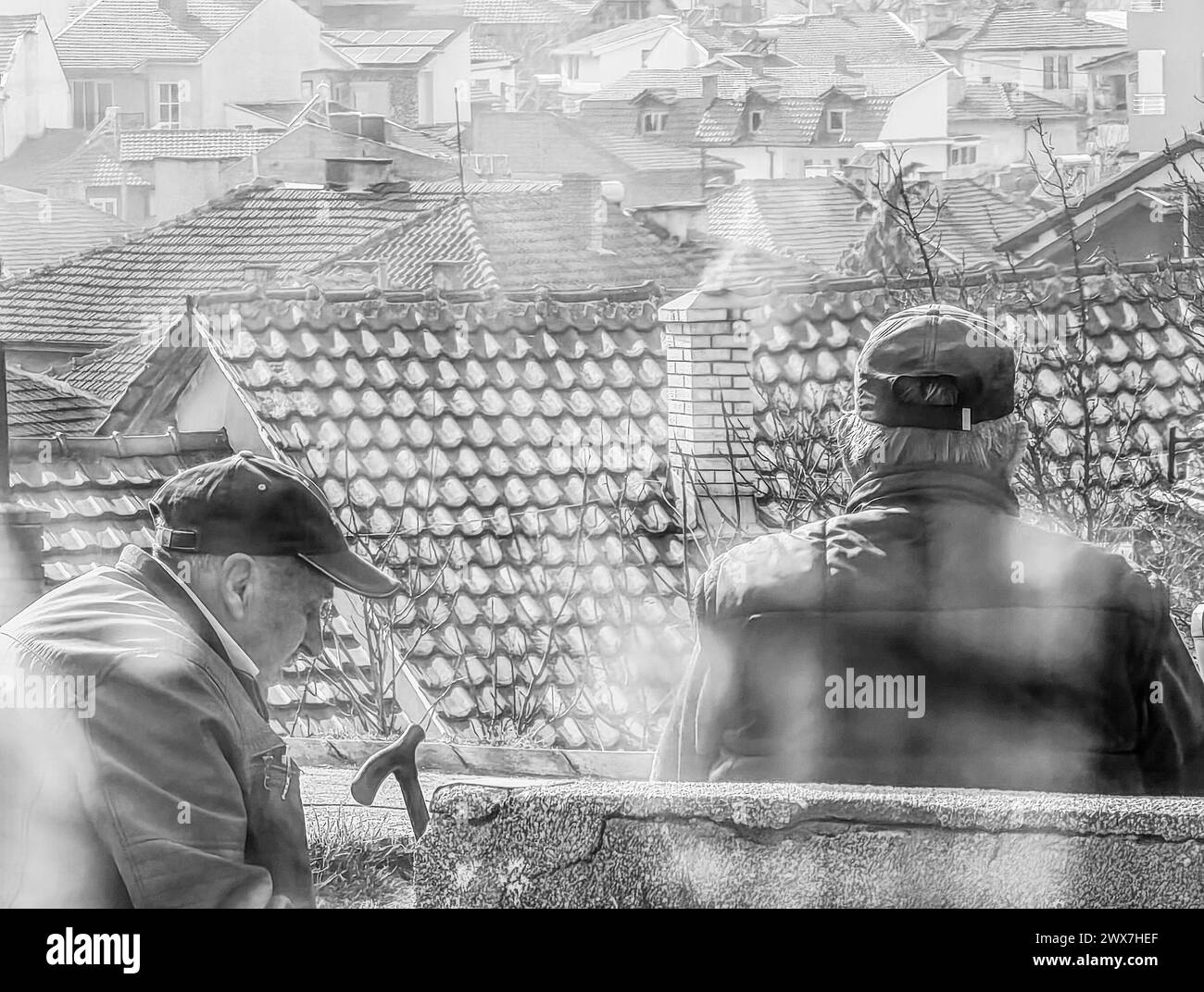 Weisheit in Monochrom: Ältere Männer Unterhaltung im Kaminrauch auf dem Dach.2. 20. 2024 Shtip Mazedonien Stockfoto