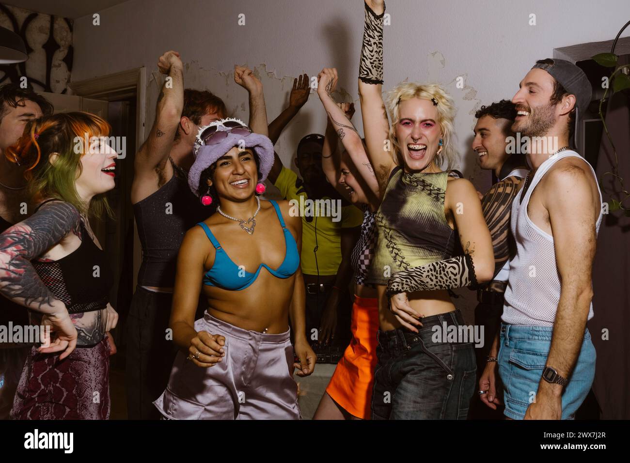 Sorglose Gruppe von nicht-binären Freunden, die auf einer Party in der Wohnung tanzen Stockfoto