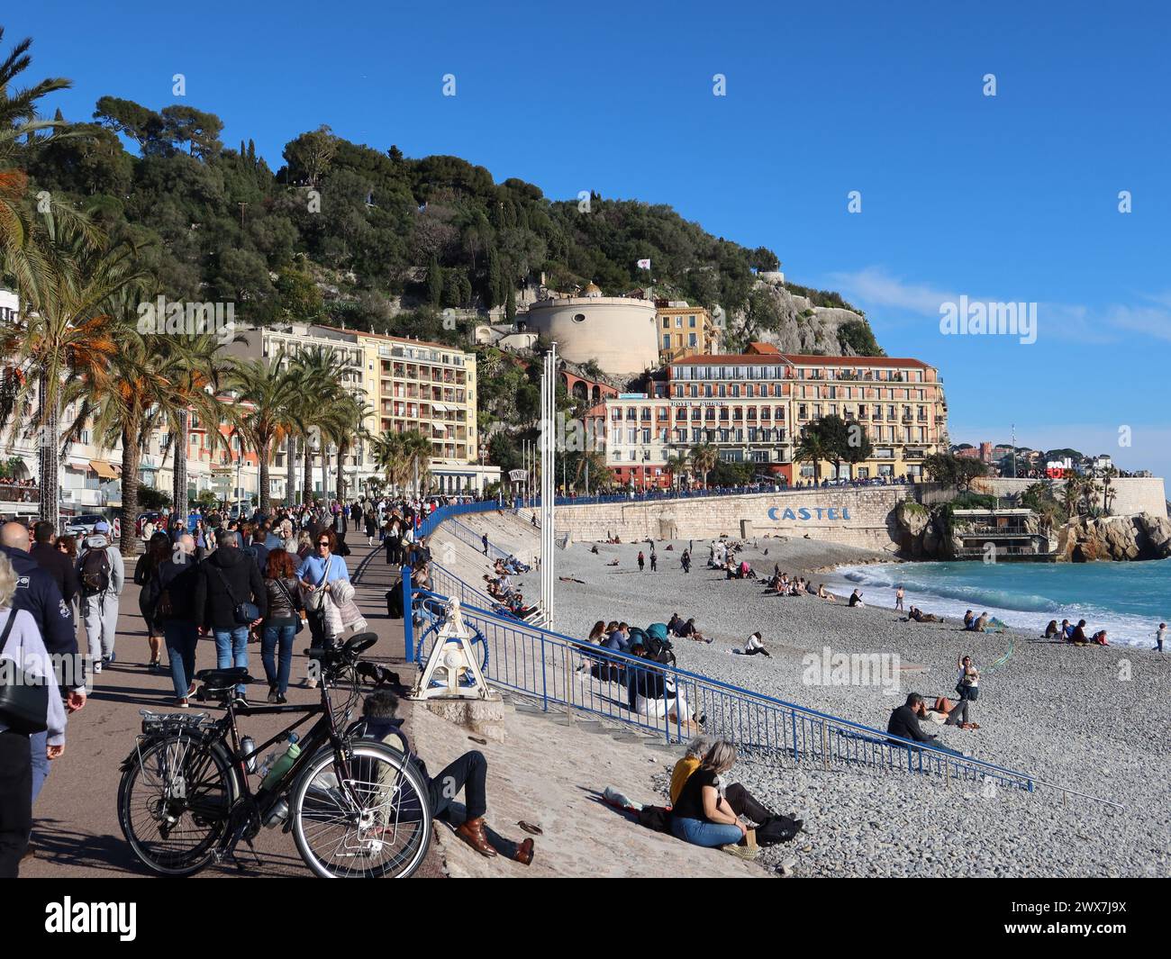 Blick auf eine geschäftige Promenade des Anglais und den Strand von Castel, Blick auf den Aussichtspunkt Tour Bellanda; Nizza, ein beliebtes Winterziel. Stockfoto