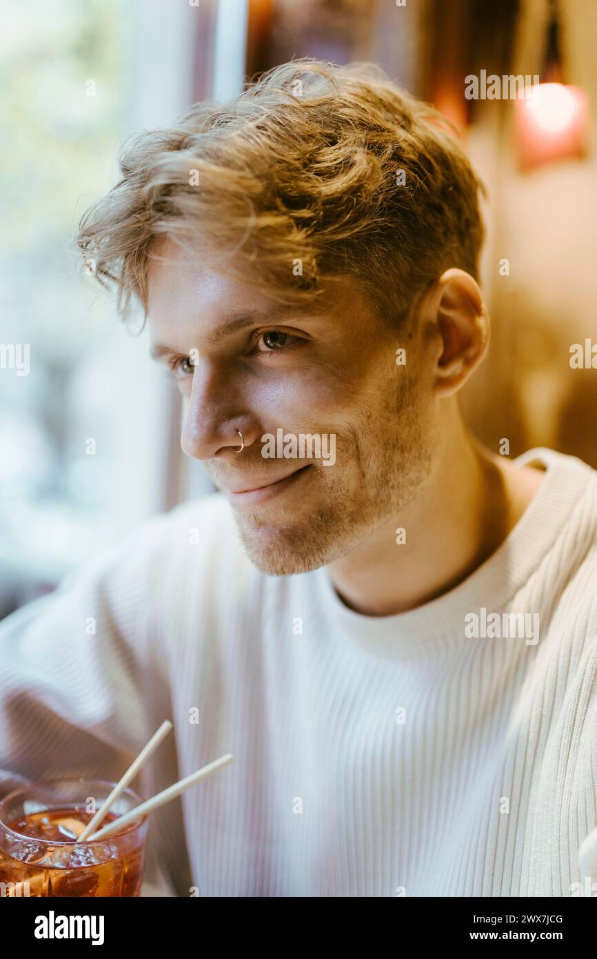 Ein lächelnder Mann trägt einen Nasenring, während er an der Bar Drinks trinkt Stockfoto