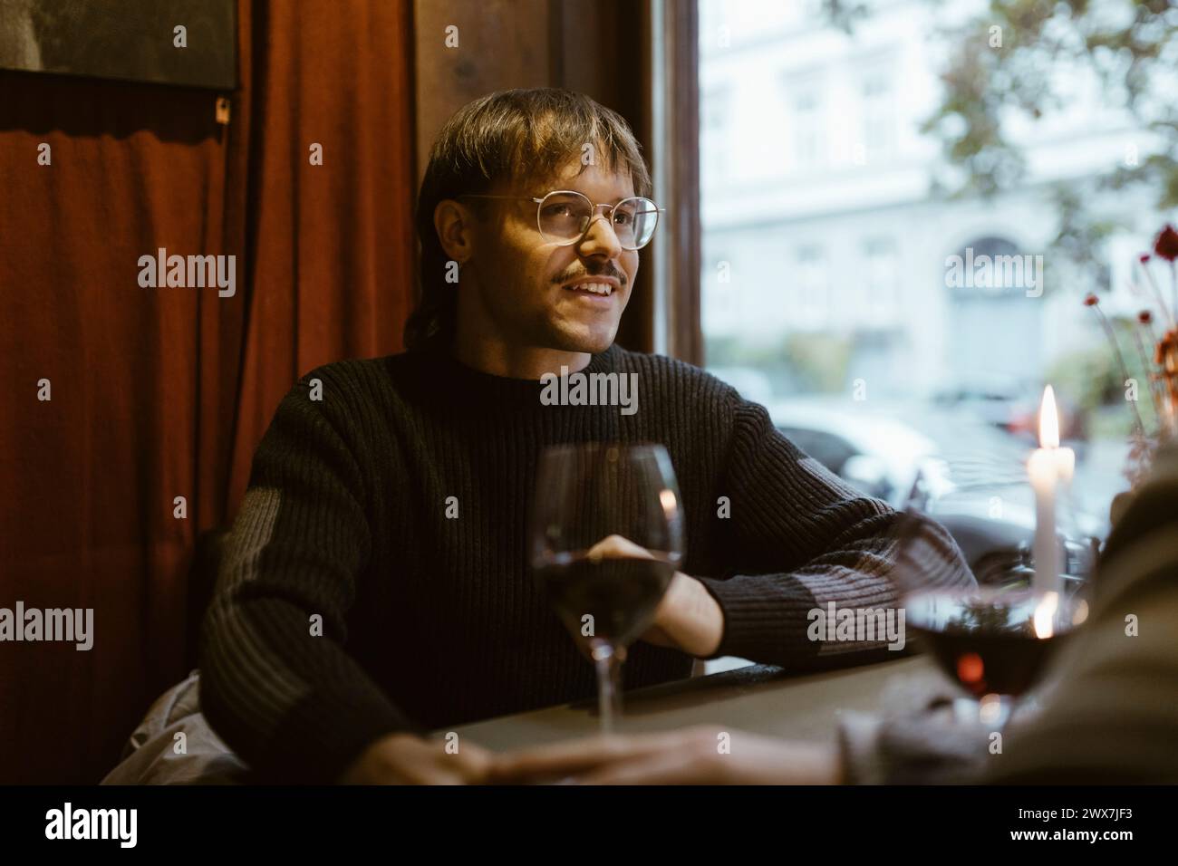 Schwuler Mann, der eine Brille trägt und mit seinem Freund im Restaurant redet Stockfoto