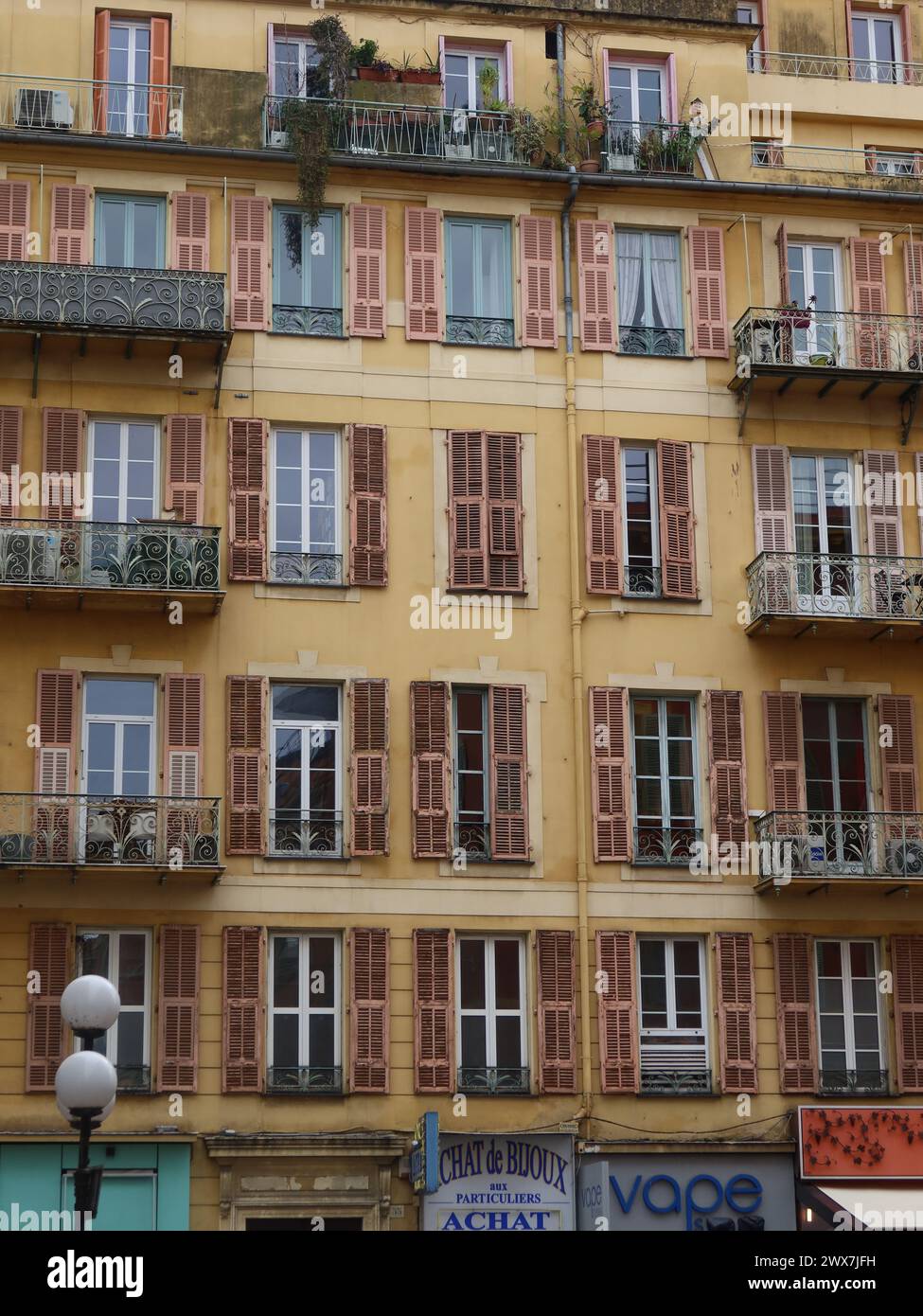 Typisch französische Architektur in der Stadt Nizza mit einem mehrstöckigen Wohngebäude mit Fensterläden an den hohen Fenstern und Balkonen. Stockfoto