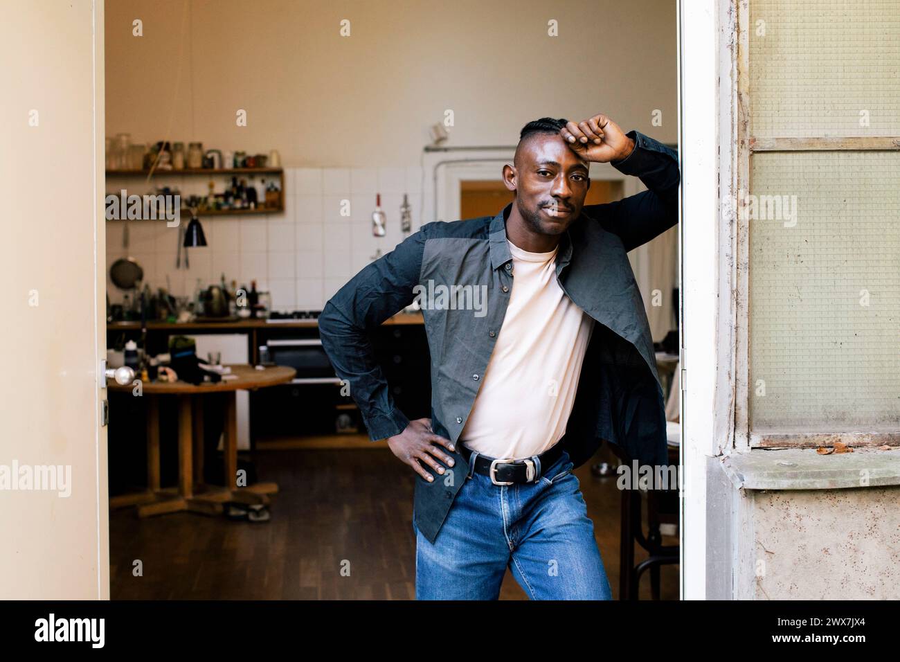 Porträt eines Geschäftsmannes mit Hand auf Hüfte, der an der Tür der Werkstatt gelehnt ist Stockfoto