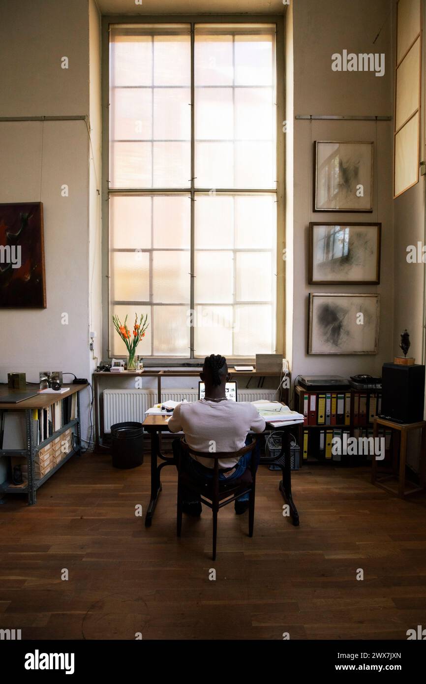 Rückansicht eines Geschäftsmannes, der am Laptop arbeitet, während er am Arbeitsplatz sitzt Stockfoto
