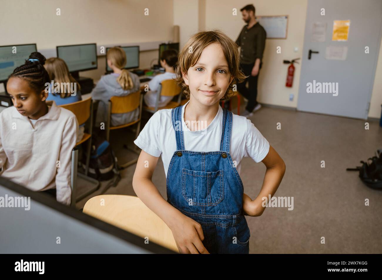 Porträt eines lächelnden Mädchens, das mit Hand auf Hüfte im Computerunterricht im Büro steht Stockfoto