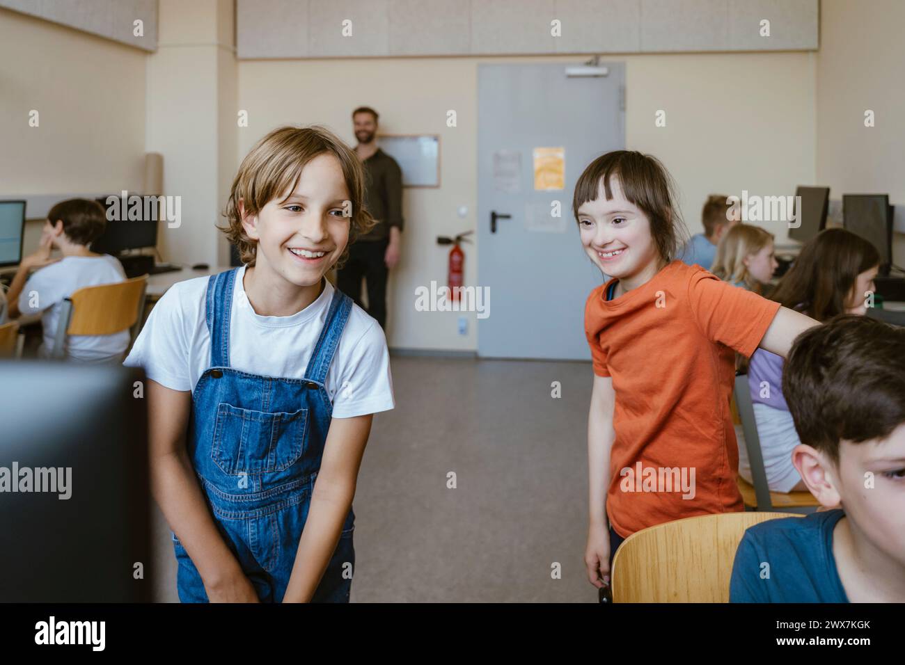 Glückliches Mädchen, das Spaß mit einer behinderten Freundin im Computerunterricht hat Stockfoto